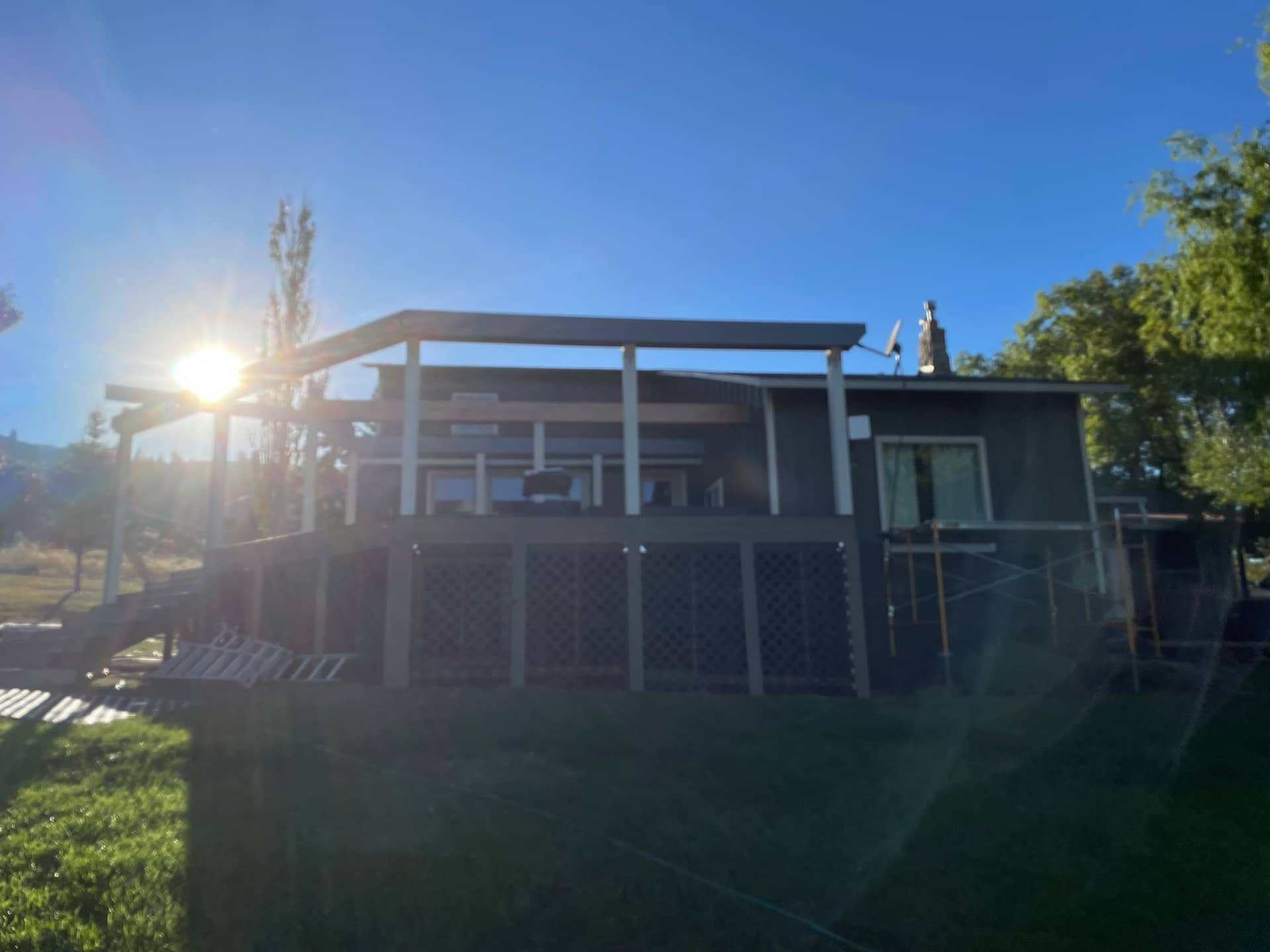 image of a deck on a gray house with the sun in the background causing a lens flare